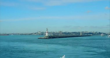 İstanbul limanındaki modern beyaz ve kırmızı deniz fenerinde uçan martılarla uçmak. Akdeniz sakinliği dalgaları. Birçok beton şamandıralar. İskele dalgaları.