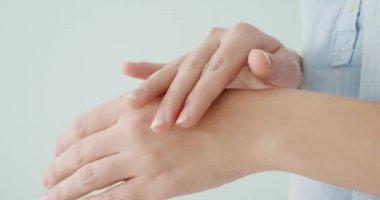 Beyaz arka plana el kremi sürerken kadın ellerini yakın plan çek.