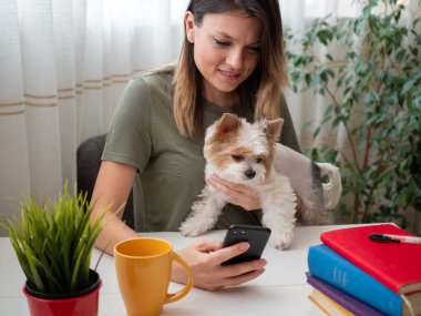 Kız arkadaşıyla cep telefonu ve şirin beyaz köpek yavrusuyla sohbet ediyor.