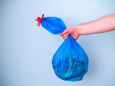 Mavi arka planda izole edilmiş mavi plastik çöp torbası kullanan erkeklerin elleri