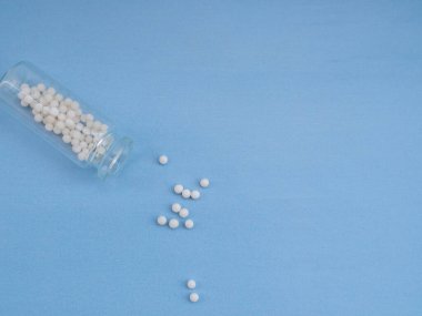 Mavi arka planda homeopatik globullar ve cam şişe. Homeopatik Tıp