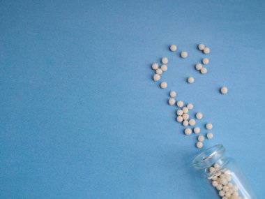 Mavi arka planda homeopatik globullar ve cam şişe. Homeopatik Tıp