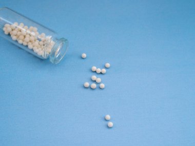 Mavi arka planda homeopatik globullar ve cam şişe. Homeopatik Tıp