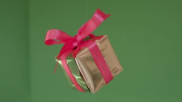 Подарочная коробка с красной лентой, вращающейся на зеленом фоне. 360 градусов вращения — стоковое видео