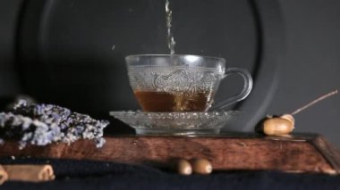 Çay bardağa doldurulur, koyu arkaplan.