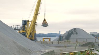 Sarı Ekskavatör moloz yığını bir nehir önünde içki alıyor. Kabloları üzerinde askıya onun kova.
