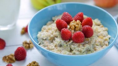 sağlıklı kahvaltı - yulaf ezmesi taze, olgun Ahududu ve ceviz ahşap bir masa üzerinde bir kase ayakta