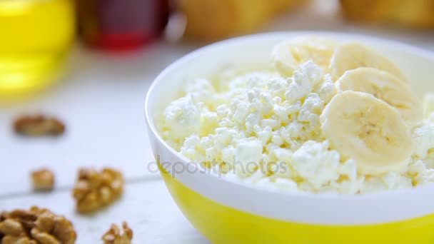 El desayuno sano - desmenuzable, el requesón con el plátano, las nueces, los croissants, la miel y la confitura de arándanos en la escudilla que se encuentra sobre la mesa de madera — Vídeos de Stock