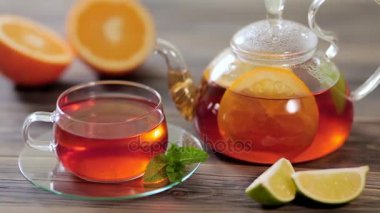Cam çaydanlık ve ahşap bir masada portakal, limon, limon ve nane ile siyah çay fincan