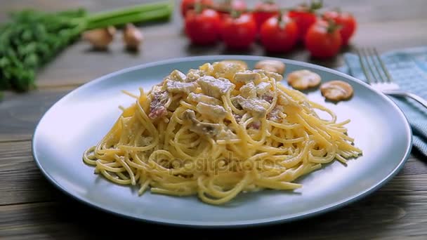 Spaghetti Carbonara con jamón y champiñones en plato azul sobre mesa de madera — Vídeos de Stock