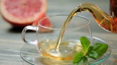 Bir çaydanlıktan siyah çayı tahta bir masaya bir bardağa döküyorum. Yakın çekim