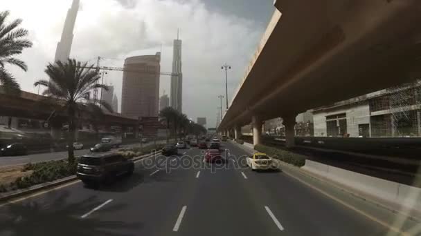 De weg wordt gedeeld met racks op de zijkanten van wolkenkrabbers vooruit en veel auto's. Dubai, Verenigde Arabische Emiraten — Stockvideo