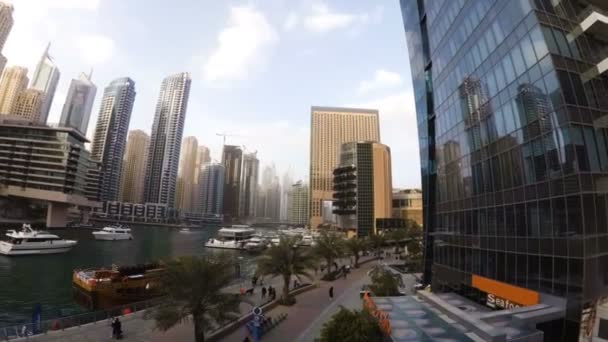 Il lungomare Dubai Marina con un lungomare dove a piedi i turisti e il canale marino dove barche a vela — Video Stock