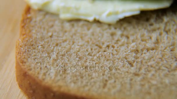 El cuchillo extiende la mantequilla sobre el pan negro — Vídeos de Stock
