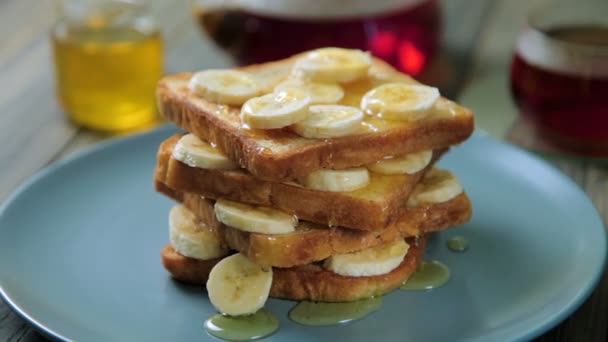 Verse zelfgemaakte krokante toast met honing en bananen op blauw bord. Heerlijk ontbijt. — Stockvideo