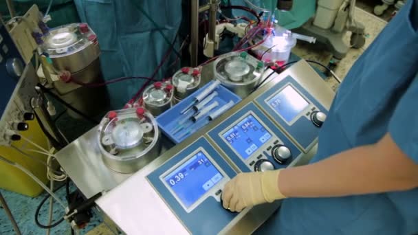 Перфузионист контролирует работу аппарата искусственного кровообращения в операционной — стоковое видео