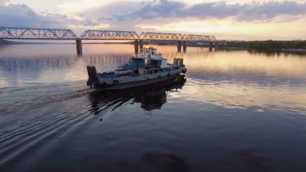 Přívoz s vozy a lidé plovoucí podél železničního mostu při západu slunce. Letecký pohled — Stock video