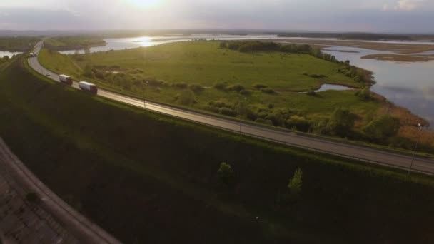 Bela paisagem com um passeio na estrada os caminhões e alguns carros ao pôr do sol. vista aérea — Vídeo de Stock