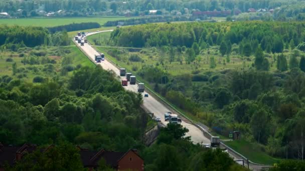 Велика кількість вантажівок і автомобілів, що їздять по довгій дорозі серед лісів і полів. Тімелапсе — стокове відео