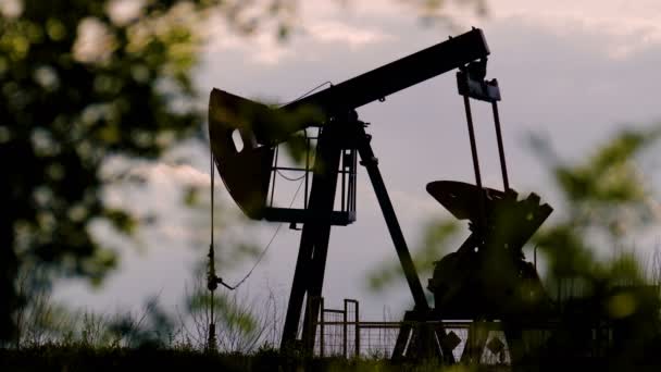 Silhouet van de oliepomp werken op een achtergrond van wolken — Stockvideo
