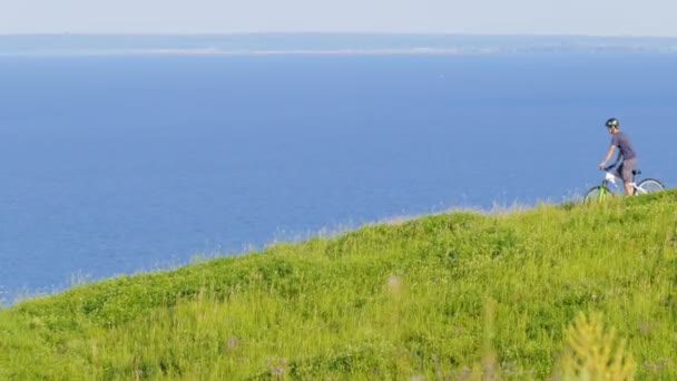 Cyklista rozhlédne a pohybuje se ze zeleného kopce — Stock video