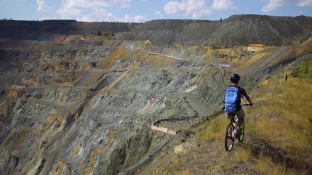 Un joven en bicicleta pasea por el acantilado del cañón — Vídeo de stock