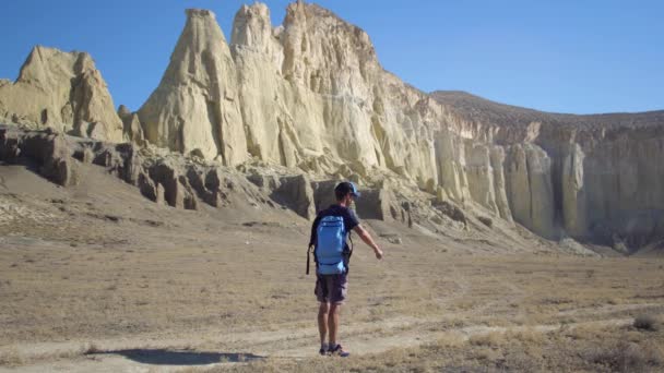 Un joven viajero bebe agua contra las rocas — Vídeos de Stock