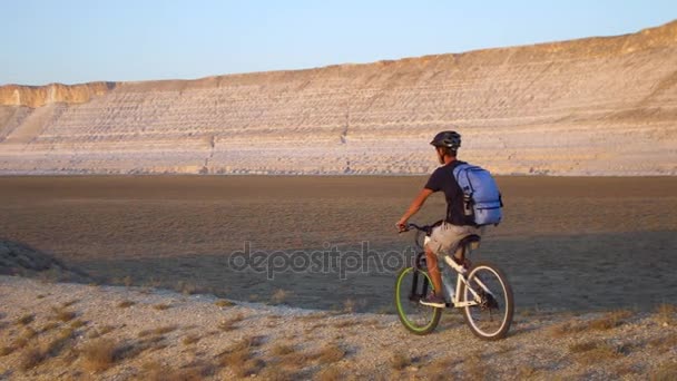 Joven montando en bicicleta sobre el fondo de un paisaje con montañas — Vídeo de stock