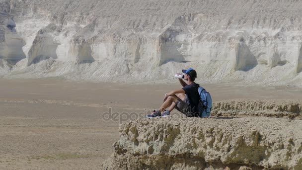 年轻的旅行者喝水在岩石上撞 — 图库视频影像