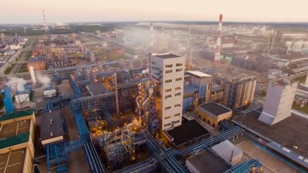 Uma enorme refinaria de petróleo com estruturas metálicas, tubos e destilação do complexo com luzes acesas ao entardecer. Vista aérea — Vídeo de Stock