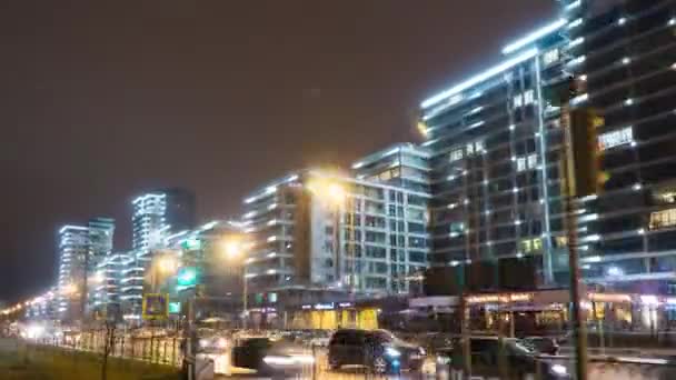 Ciudad nocturna con grandes edificios residenciales iluminados por luces y coches. Hiperlapso — Vídeos de Stock