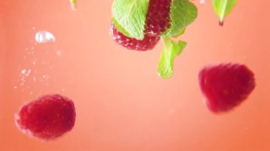 Ahududu ve turuncu zemin üzerine düşen suya nane. Makro görünümü