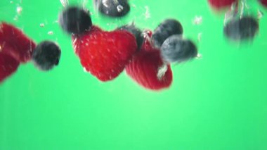 yaban mersini ve ahududu yeşil zemin üzerine suya serpilir. Makro görünümü