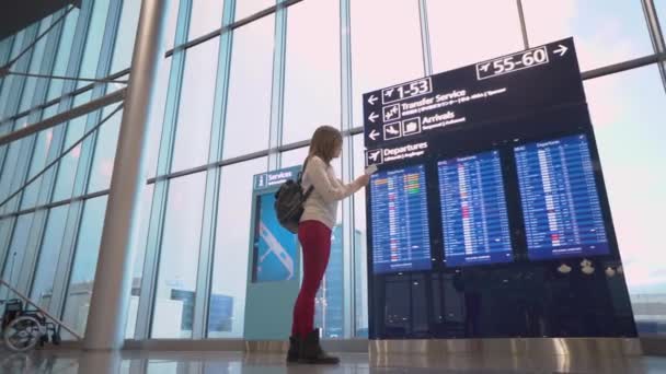 Helsinki, Finnland - 14.01.2018: Junge Frau am internationalen Flughafen schaut auf die Fluginformationstafel und checkt ihren Flug — Stockvideo