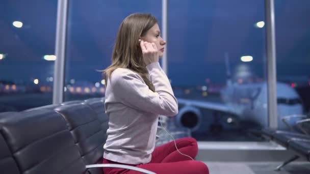 Beautiful young casual woman doing yoga meditation in an empty airport terminal against the background of an aircraft — Stockvideo