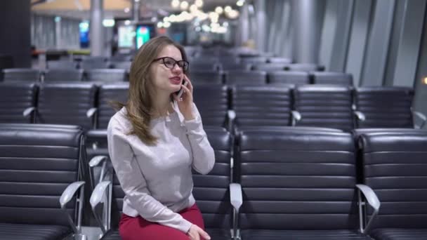 Jovem, menina bonita falando ao telefone em um terminal de aeroporto vazio — Vídeo de Stock