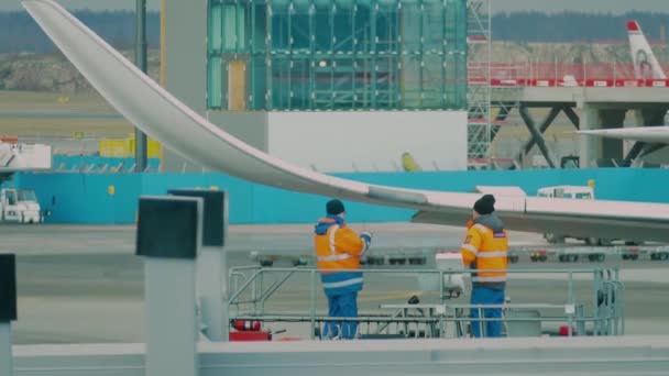 Два технических эксперта ремонтируют крыло самолета в аэропорту — стоковое видео