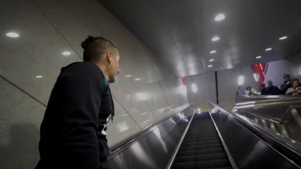 Junger Kaukasier fährt auf Rolltreppe am Flughafen, U-Bahn — Stockvideo