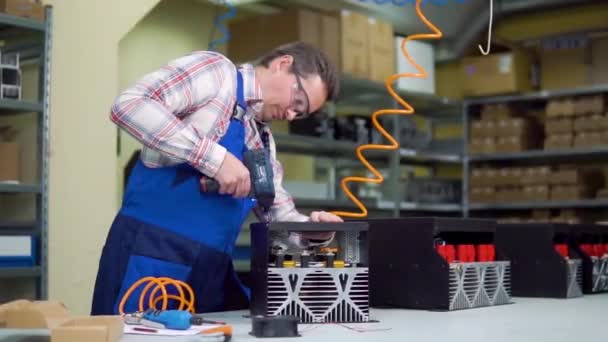 Ung arbetare i skjorta och overaller monterar elektroniska komponenter i en högteknologisk fabrik — Stockvideo
