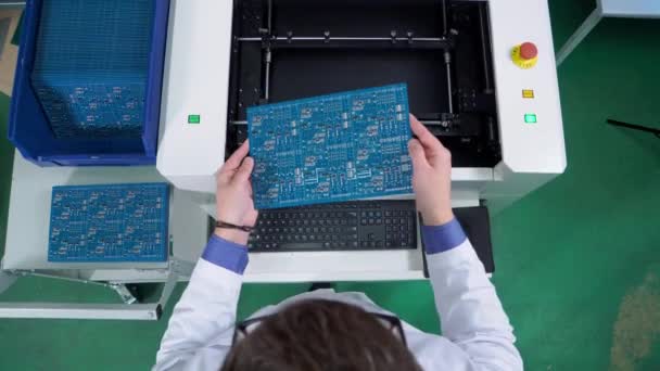 De werknemer stopt het moederbord in de apparatuur voor de inspectie van het elektrische bord. Productie van printplaten. Technologisch proces. Fabriek voor microchip — Stockvideo