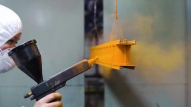 Toz boya metal parçalar. Bir kadın koruyucu kıyafetli silahtan toz boya metal ürünlerde spreyler