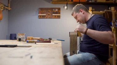 Atölyede dikiş dikmek için deri iğnesi olan adam. Bireysel tasarım için bir çanta yapıyor.
