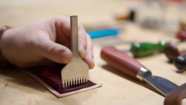 Крупним планом чоловічий майстер різання шматок шкіри з інструментами для майбутніх гаманців в майстерні. Високий кут огляду робочого місця cobbler — стокове відео