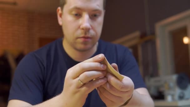 Proceso de trabajo de hacer cinturón de cuero marrón en el taller de cuero. Manos de hombre creando un nuevo cinturón con estilo. Pulido de bordes — Vídeo de stock