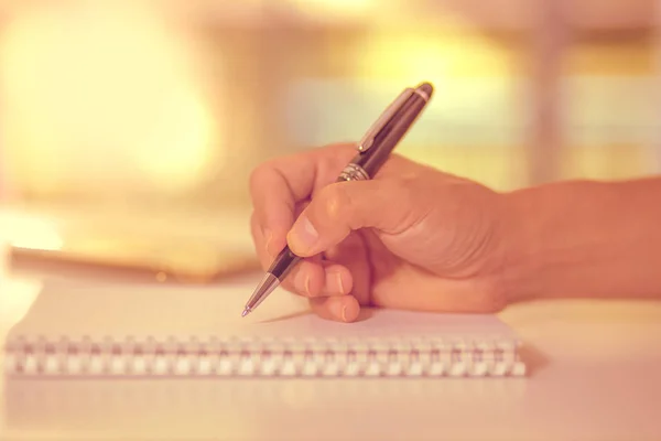 Mano de hombre sosteniendo un bolígrafo escrito en el cuaderno . — Foto de Stock