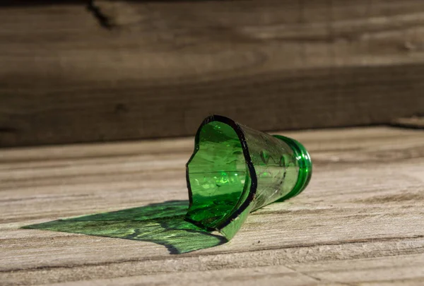 Розбита зелена скляна пляшка з дерев'яним фоном . — стокове фото