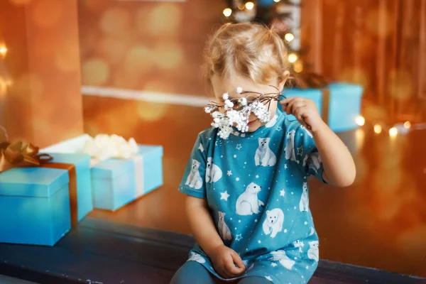 Boldog kis szőke lány pólóban, medvékkel a dekoráció mögött a karácsonyi díszítésű házban. — Stock Fotó