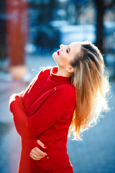 Beautiful blonde long haired woman in long sleeve red dress with red lipstick