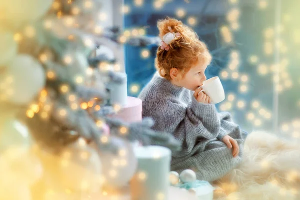 Petite fille souriante en pull oversize gris attend le Père Noël à Noël — Photo