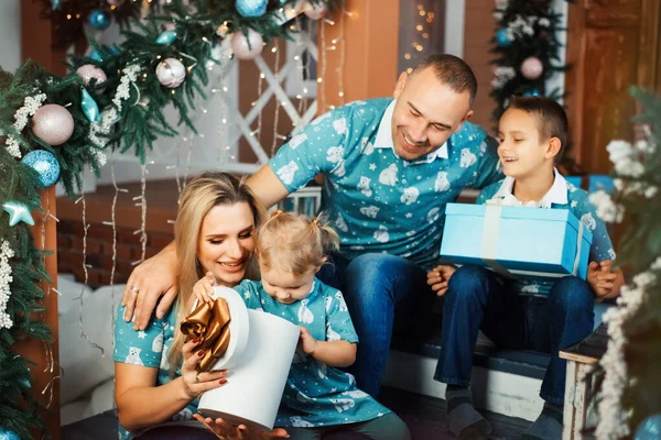Mosolygó anya és apa karácsonyi ajándékokat adnak két gyermeküknek - egy fiúnak és egy lánynak, egy fiúnak és egy lánynak, egy testvérnek és egy nővérnek. A gyerekek boldogok az ajándékokkal.. — Stock Fotó